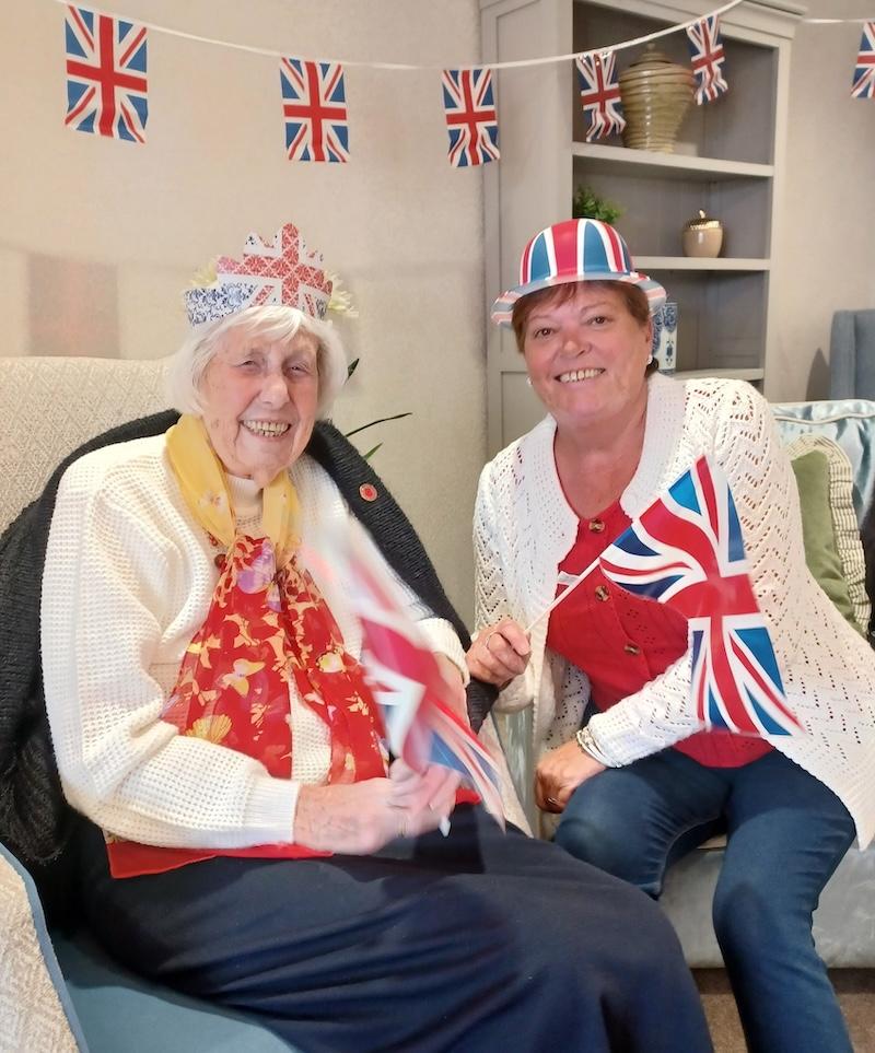 resident celebrating VE day sat smiling with a member of the team