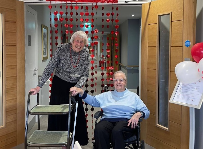 residents together holding hands with a valentines day backdrop