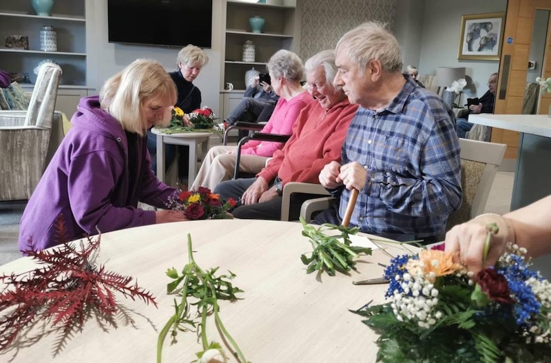 residents sat around a table doing flower arranging